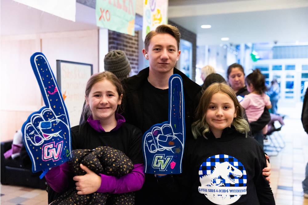Siblings smiling for a picture with their foam fingers up